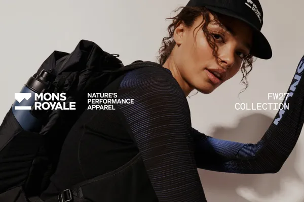 Model in a black cap and striped top wears a backpack for the Mons Royale FW27 collection.