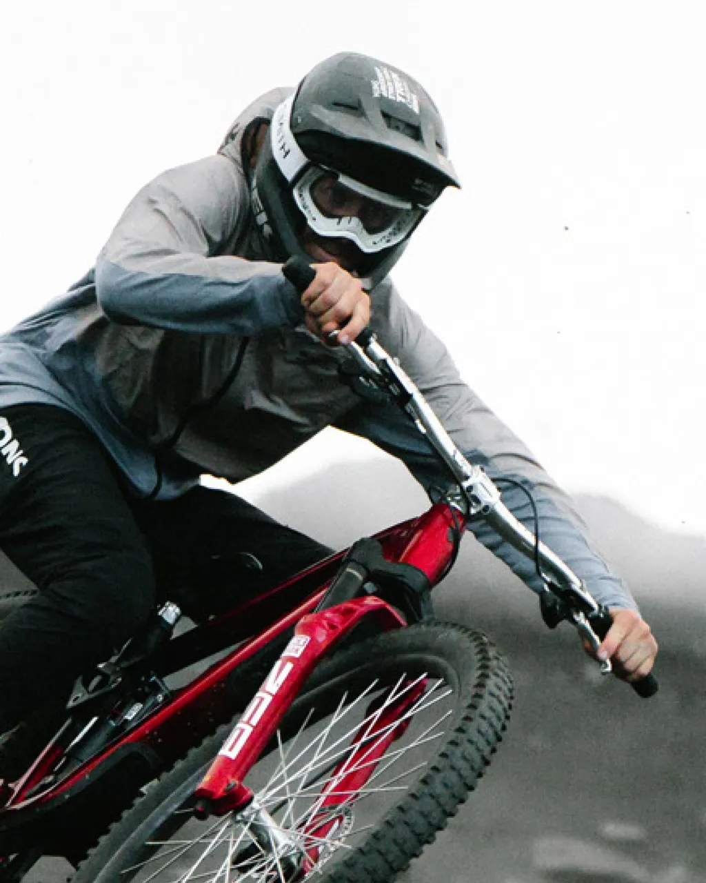 A helmeted rider leans into a turn on a red mountain bike.