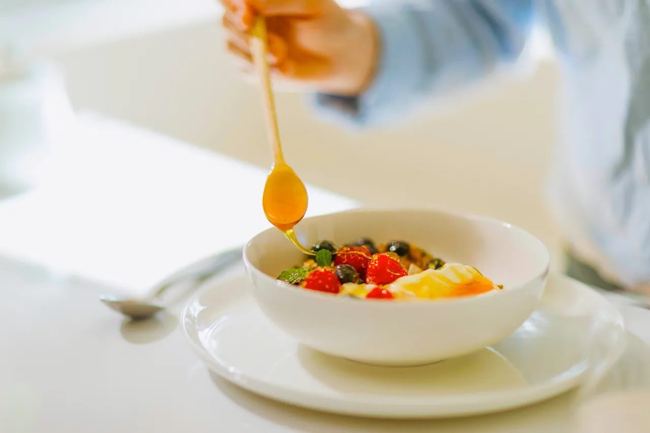 Drizzling Honey onto Breakfast Bowl