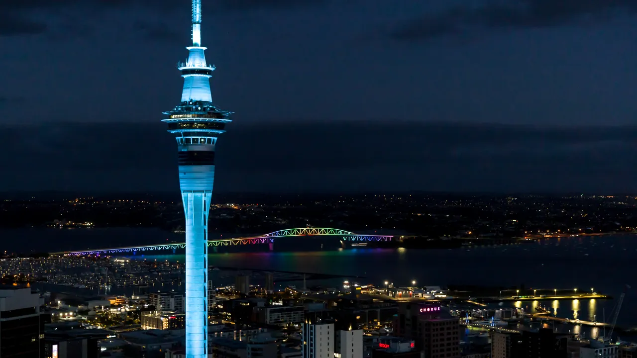 Sky Tower blue with Rainbow coloured Harbour Bridge in background
