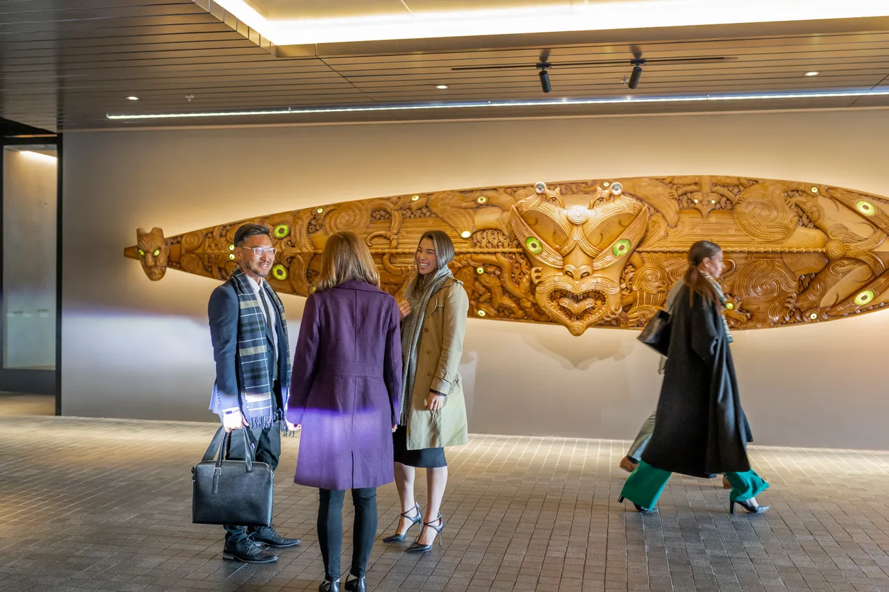 Delegates conversate in front of Maori artwork