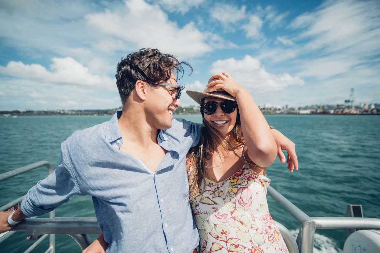 Couple smiling on a boat with Auckland Port in background