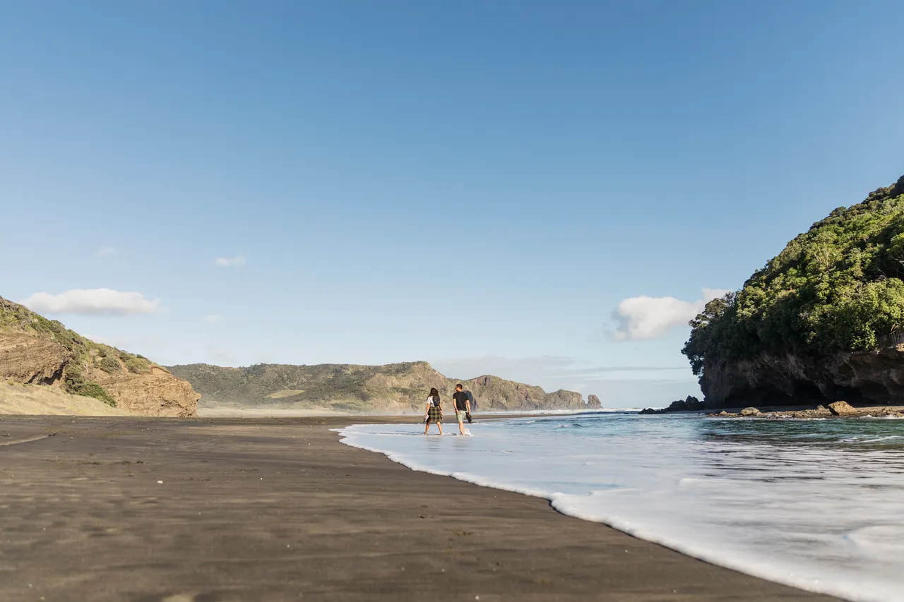 Woman and man walking along tide line