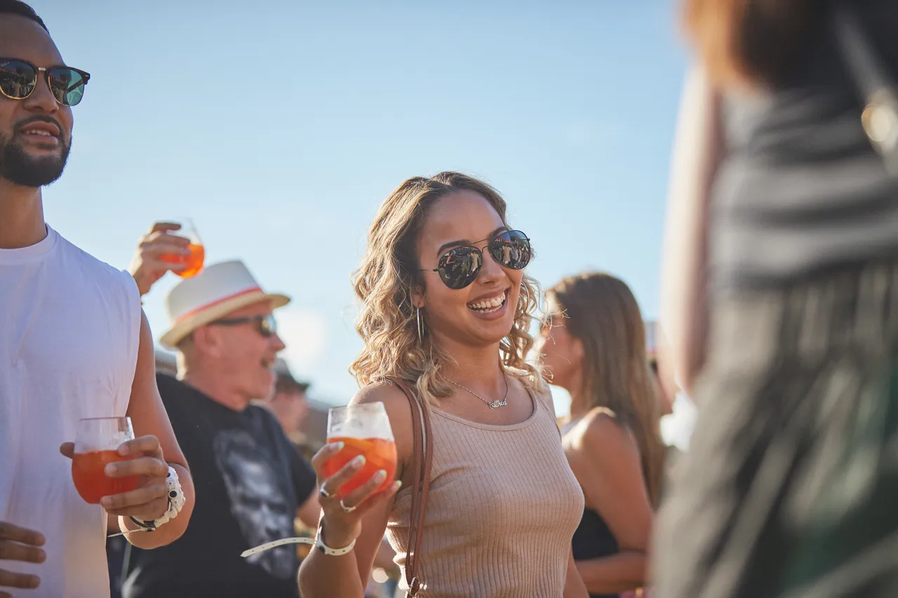 Woman smiling while holding a drink in crowd