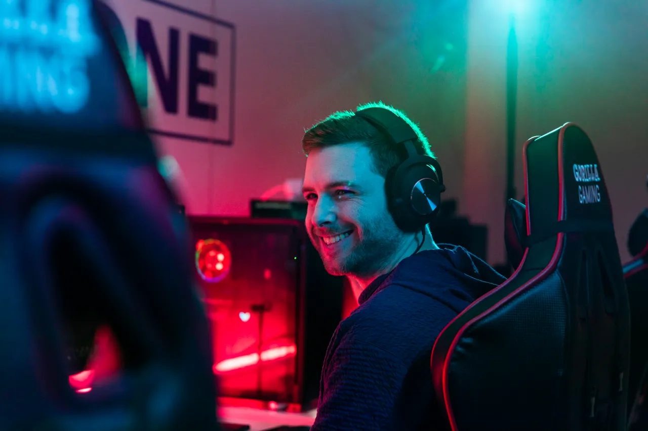 Young man with headphones behind computer smiling