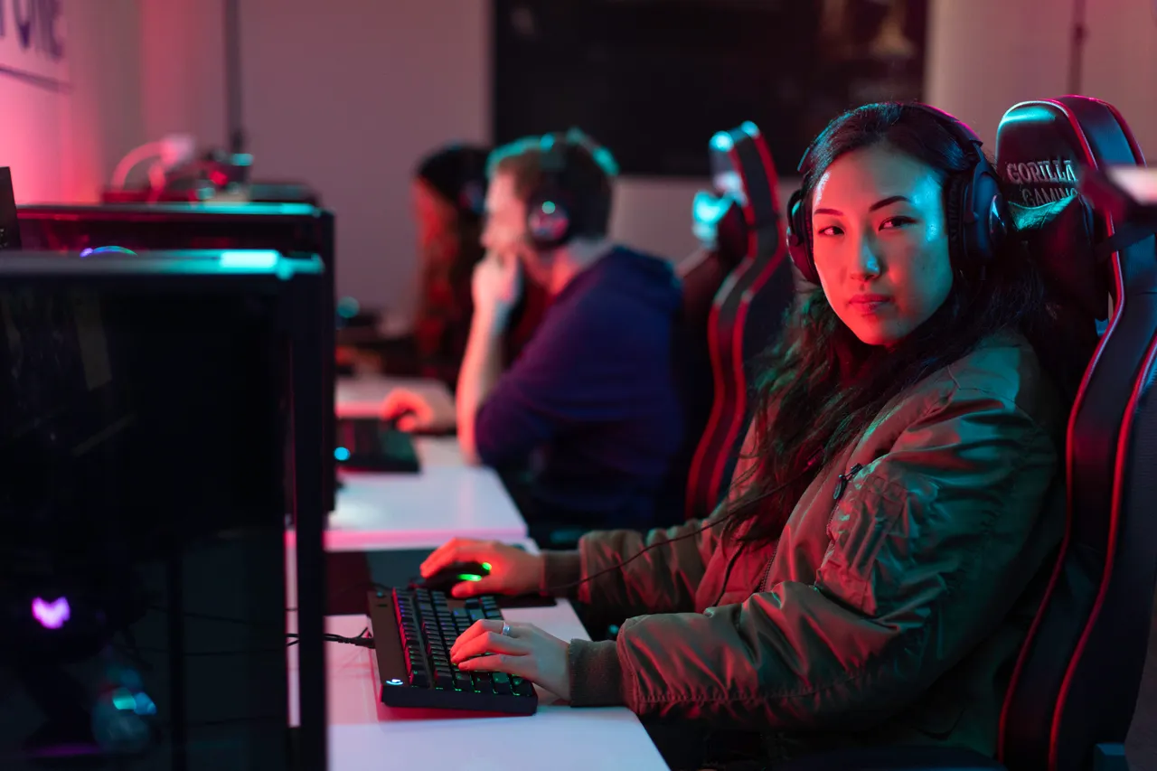 Young woman with headphones playing games on computer