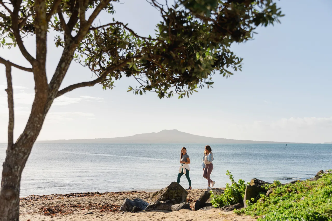 Women walk along an Auckland beach