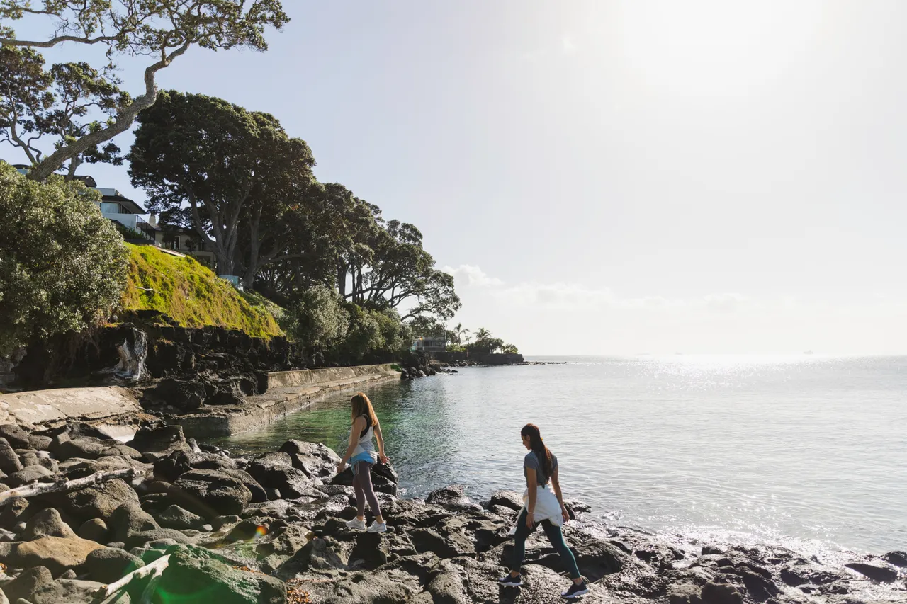 Women walking on rocks next to the sea