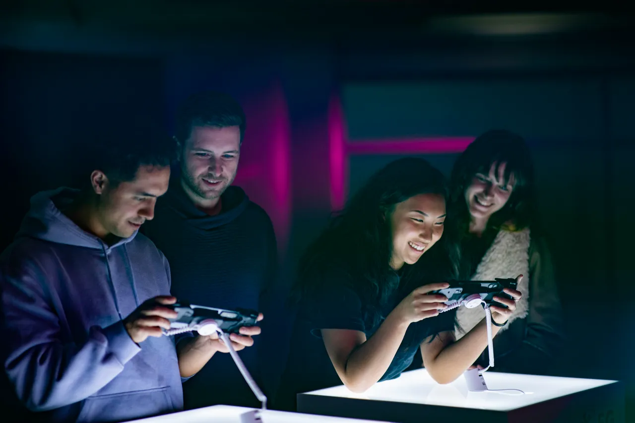 A group of young people playing games on mobile phones smiling