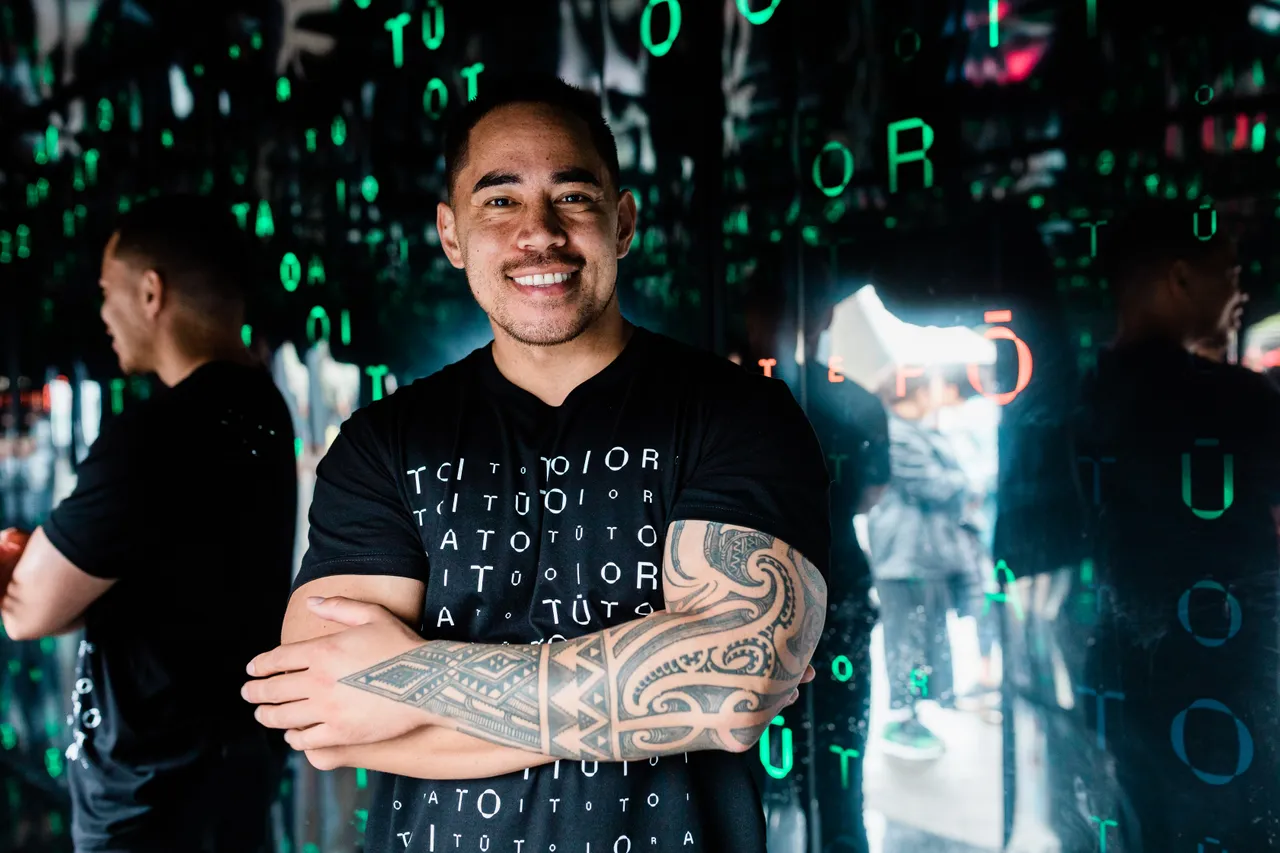 Man with folded arms and tattoos smiling to camera