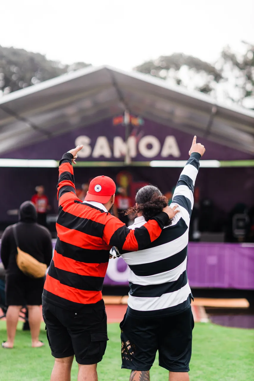 Two man in front of stage pointing their fingers up
