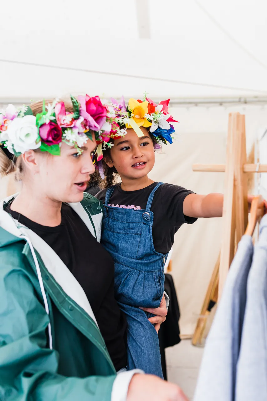 Woman holding child with head eis looking at clothes