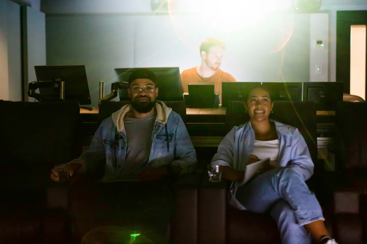 Woman and man taking notes while editor working in background in editing suite