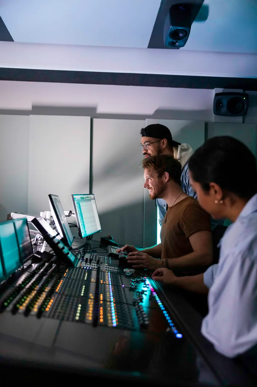 Group working on mixing desk in stuido