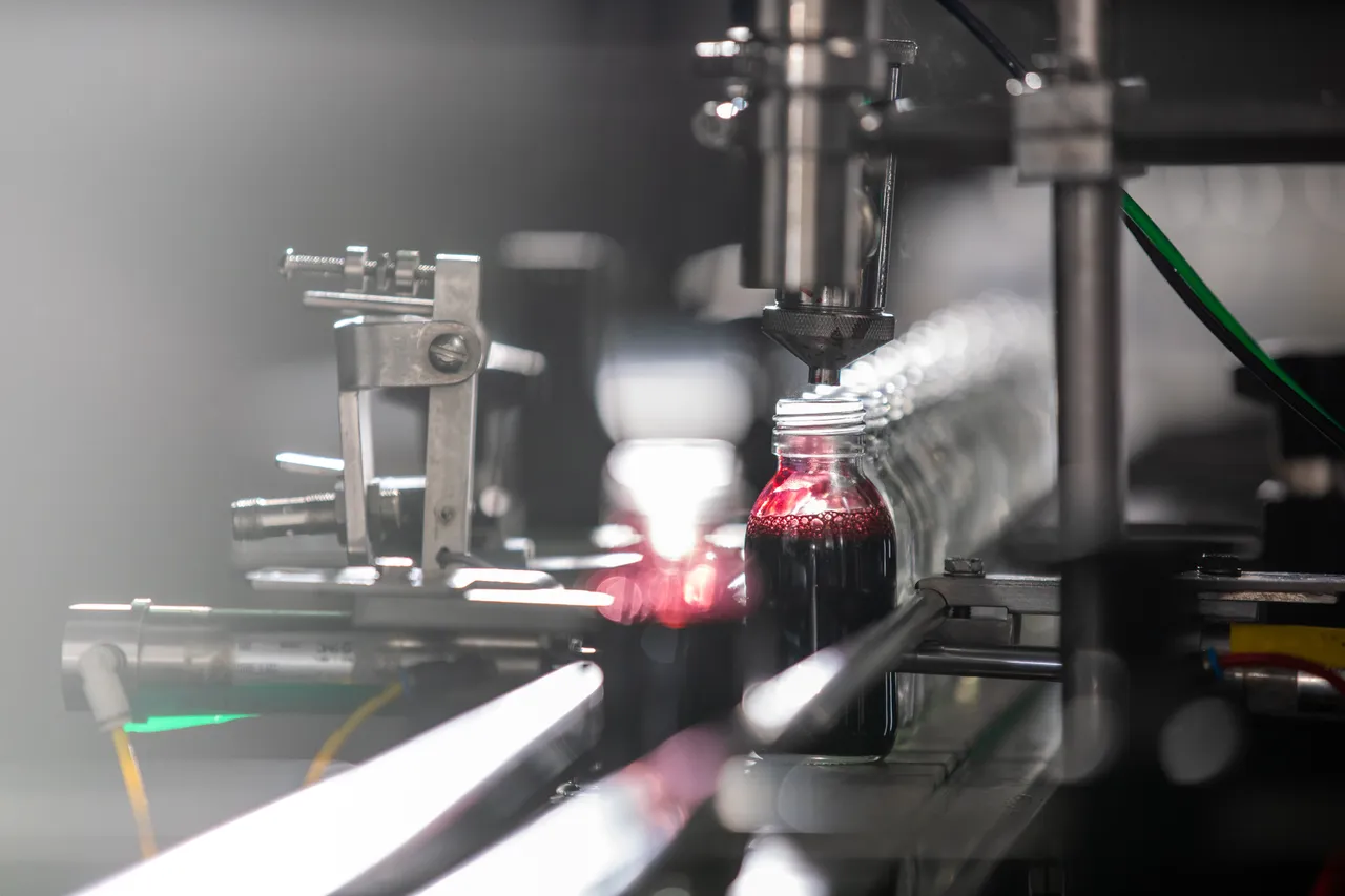 Bottle being filled on conveyor belt in factory