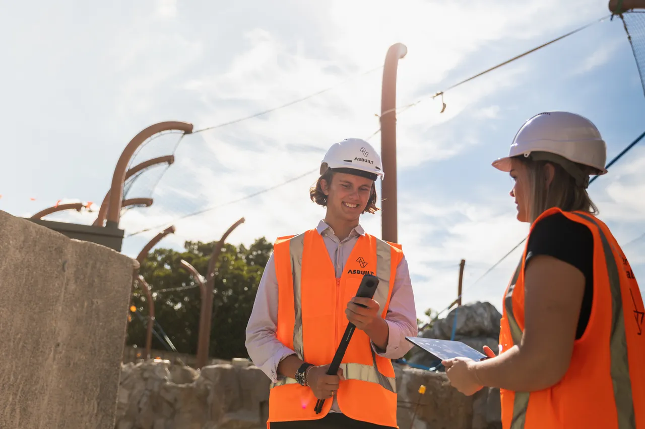 Man and woman working on construction site using 360 camera