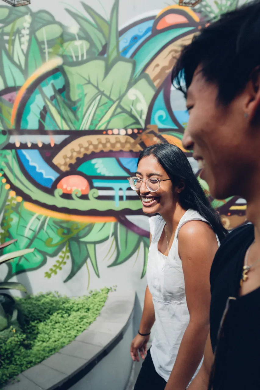 Smiley woman and man in front of mural