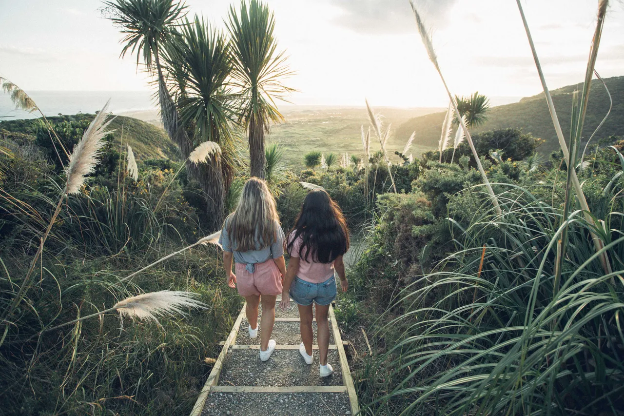 Two girls walking down stairs towards the beach