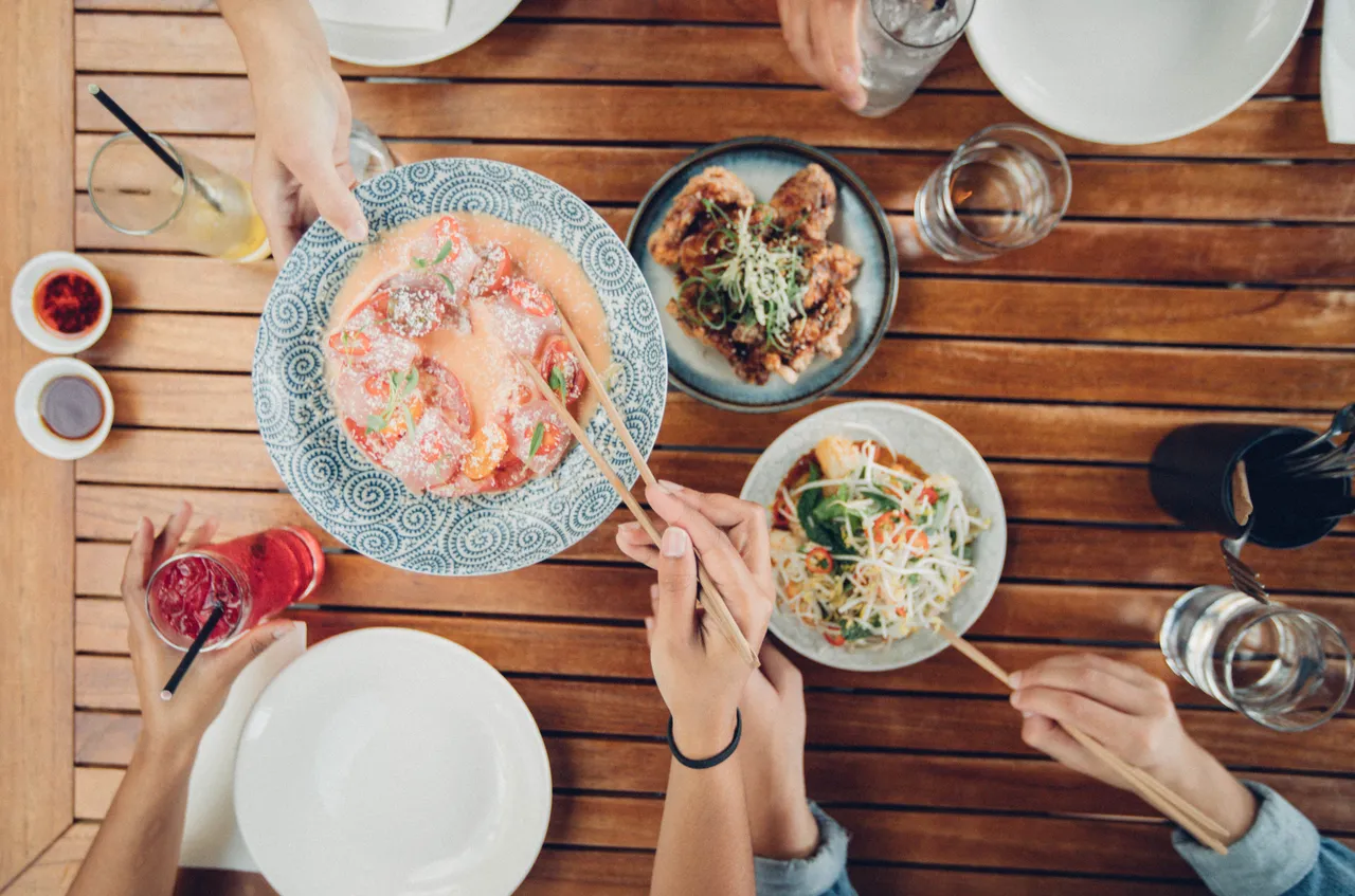 People reaching for food with chopsticks