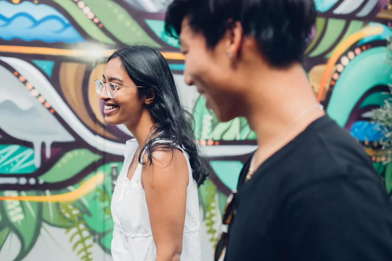 Girl and boy smiling past mural