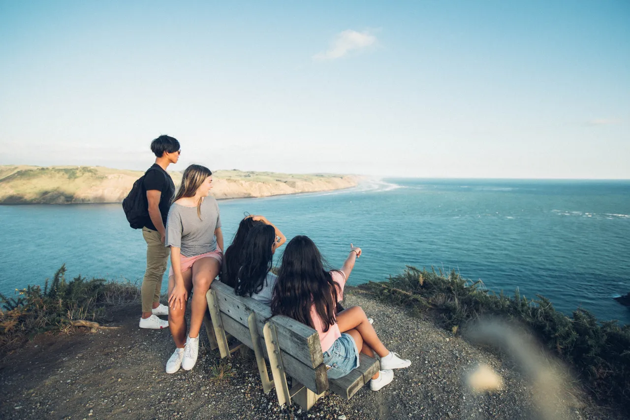 Students pointing out to ocean on cliff