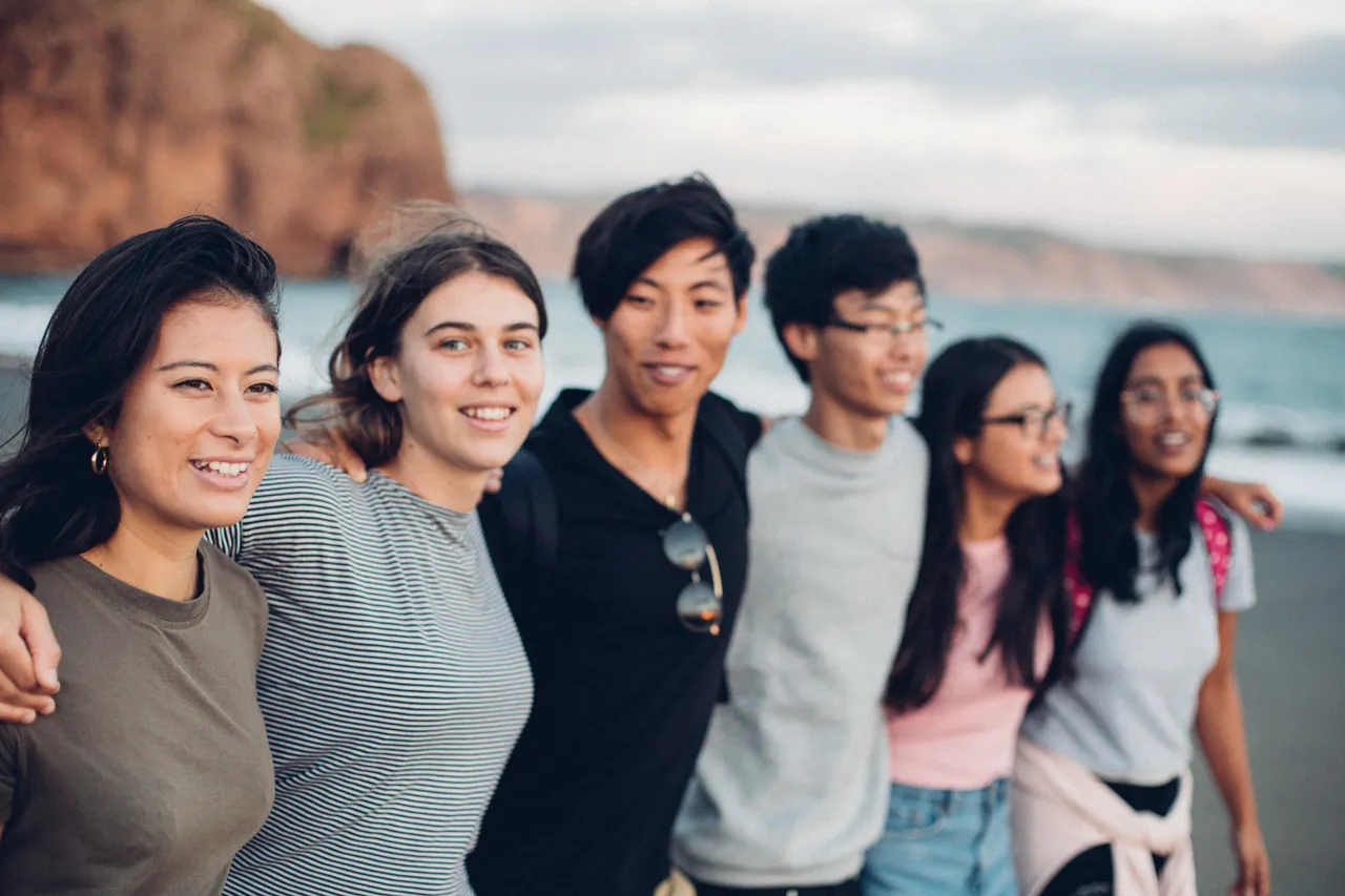 Students standing side by side on beach