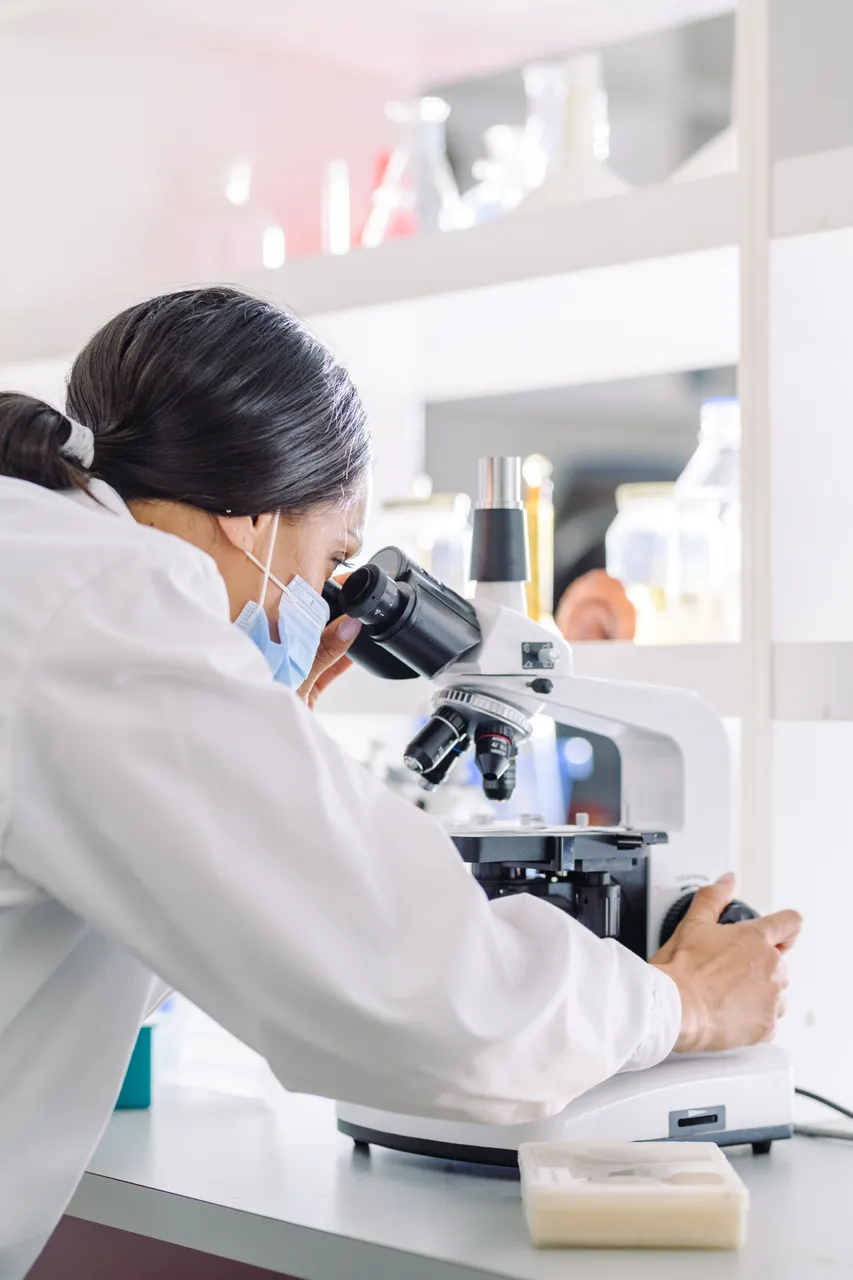 Woman with mask looking into microscope