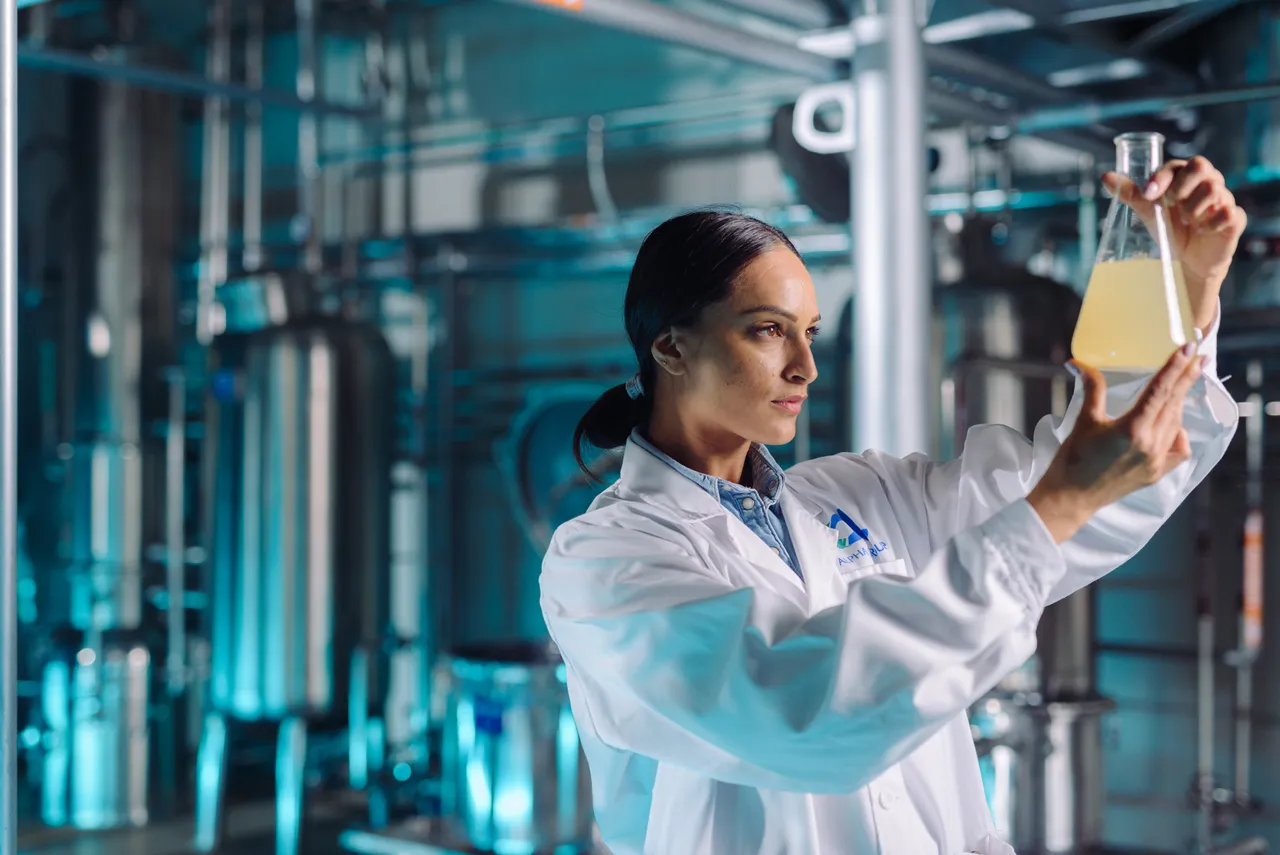 Woman holding up flask in fermentation plant