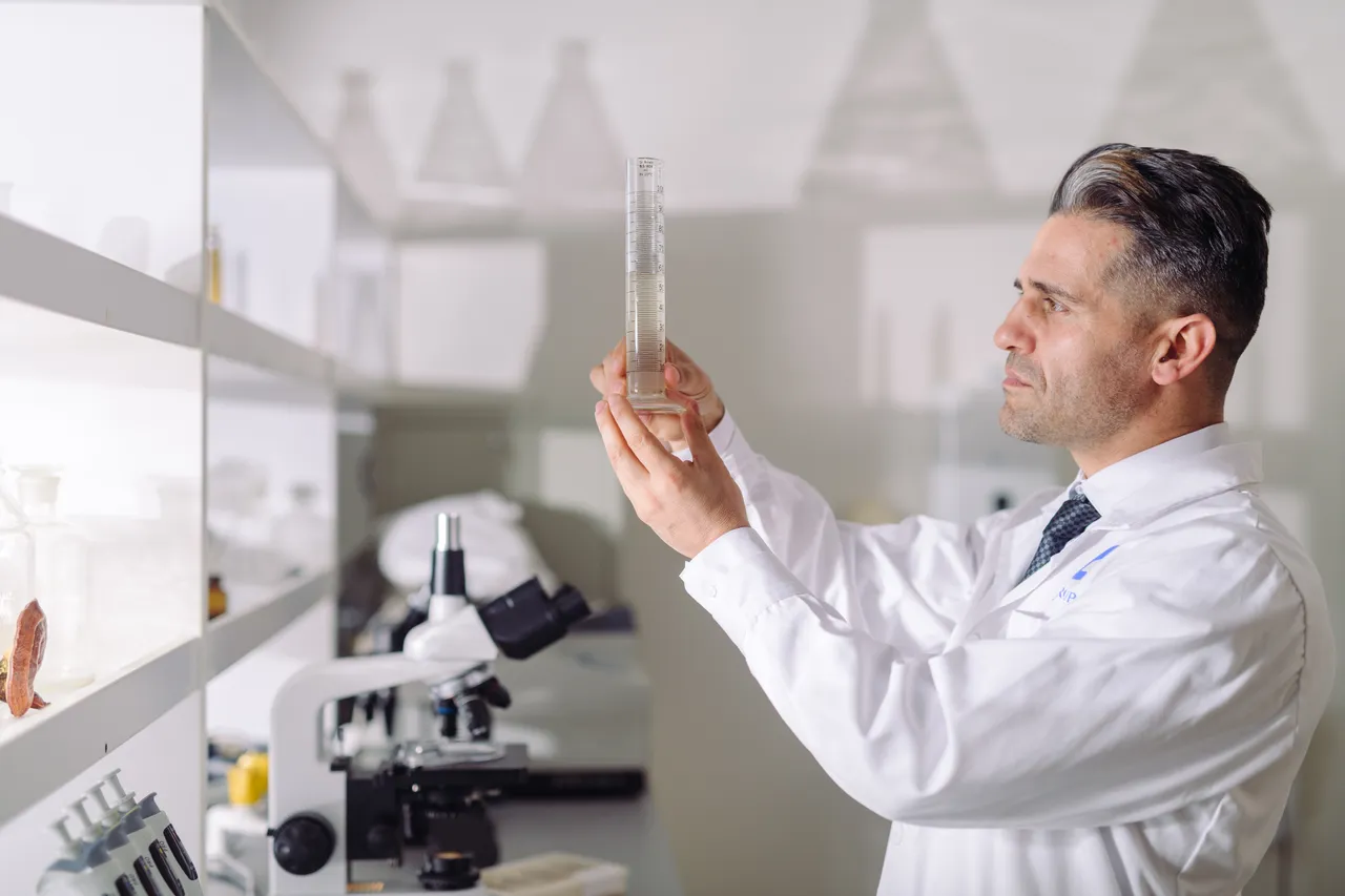 Man holding up beaker in scientific research lab