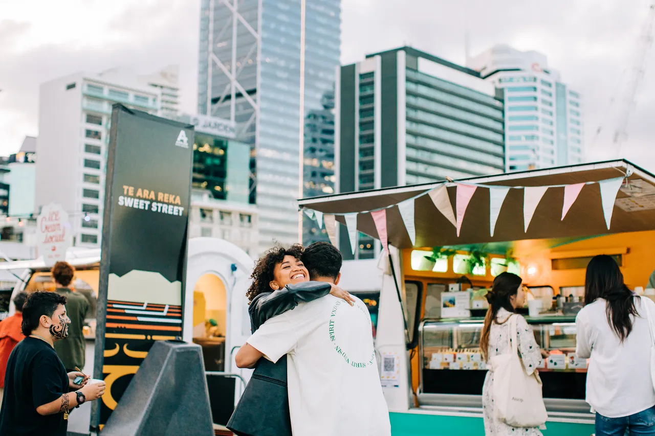 Couple hugging outside food stalls in Auckland city