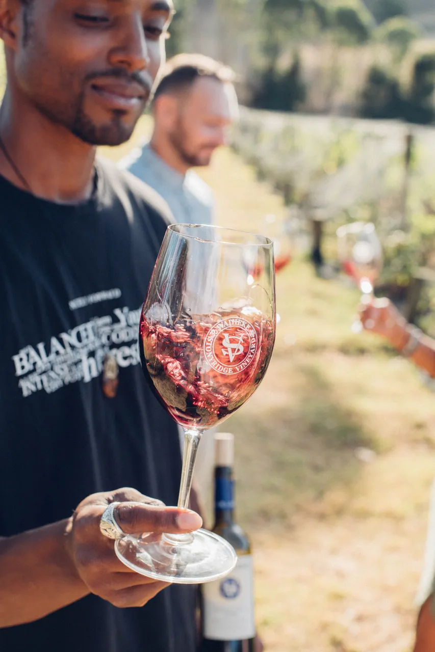 Young man swills a glass of red wine on Waiheke