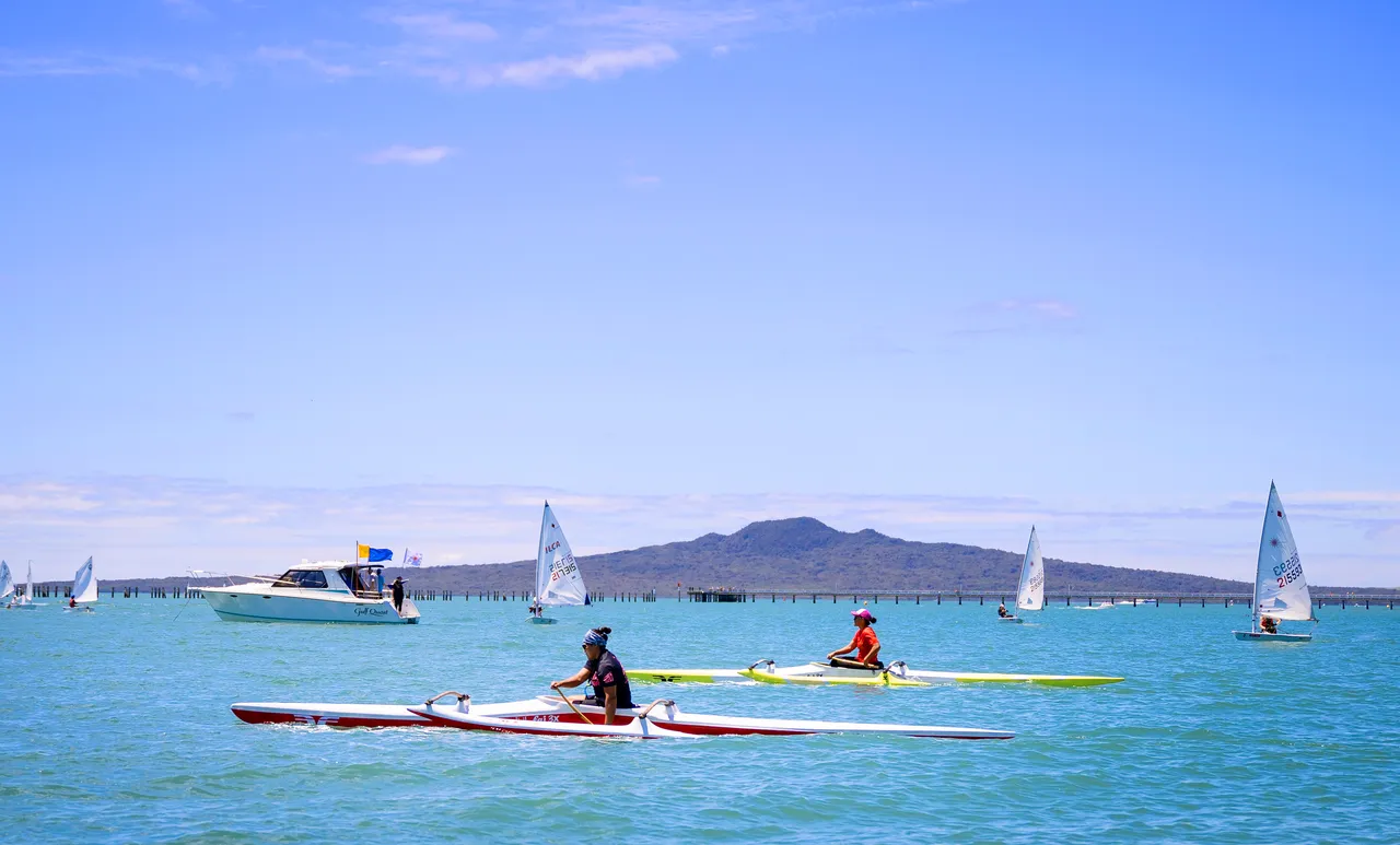 Pair paddle rudderless outrigger canoes in Waitematā Harbour
