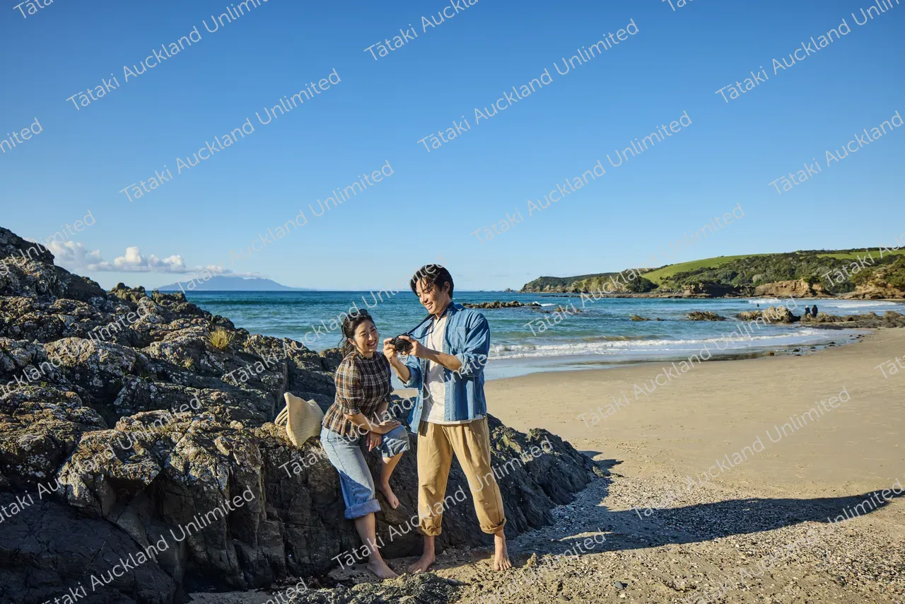 Couple walk on Tāwharanui Beach 6