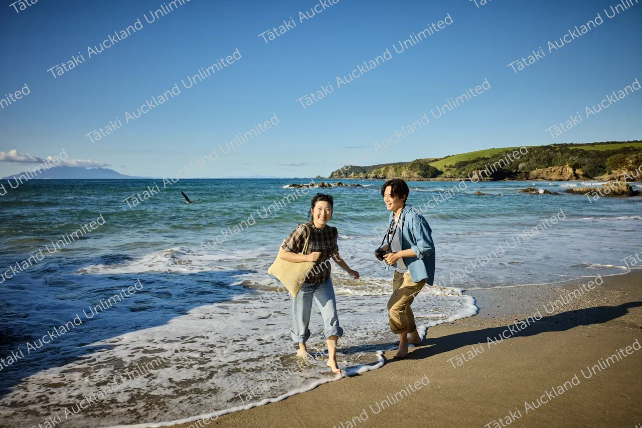 Couple walk on Tāwharanui Beach 5