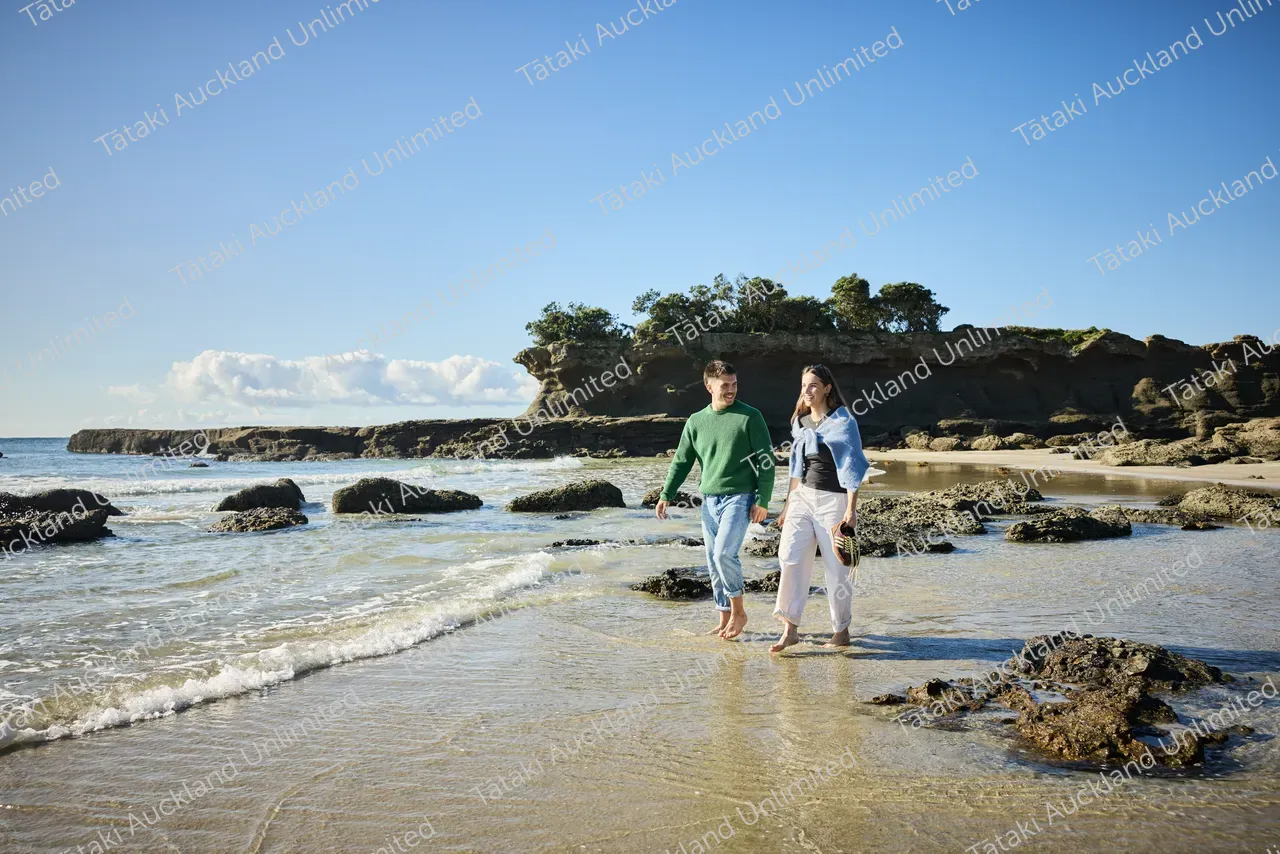 Couple walk on Tāwharanui Beach 3