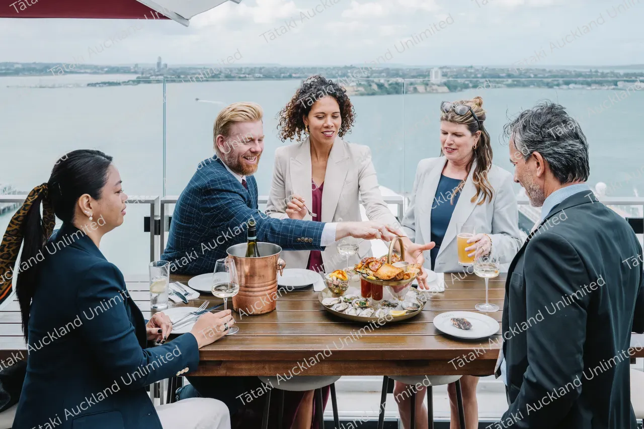 Five business professionals share a rooftop terrace meal 