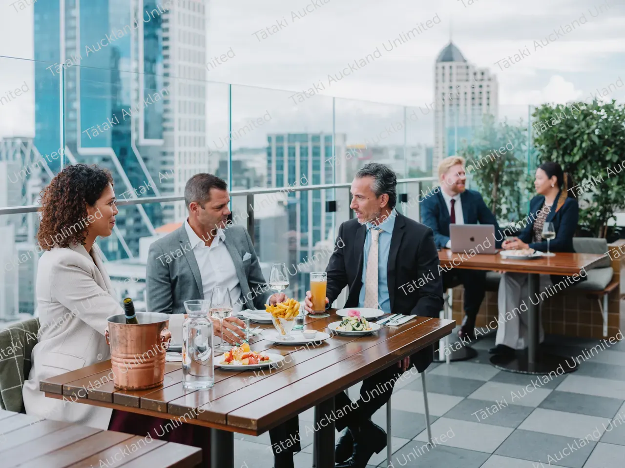 Business professionals dine on a rooftop terrace with city skyline views 2