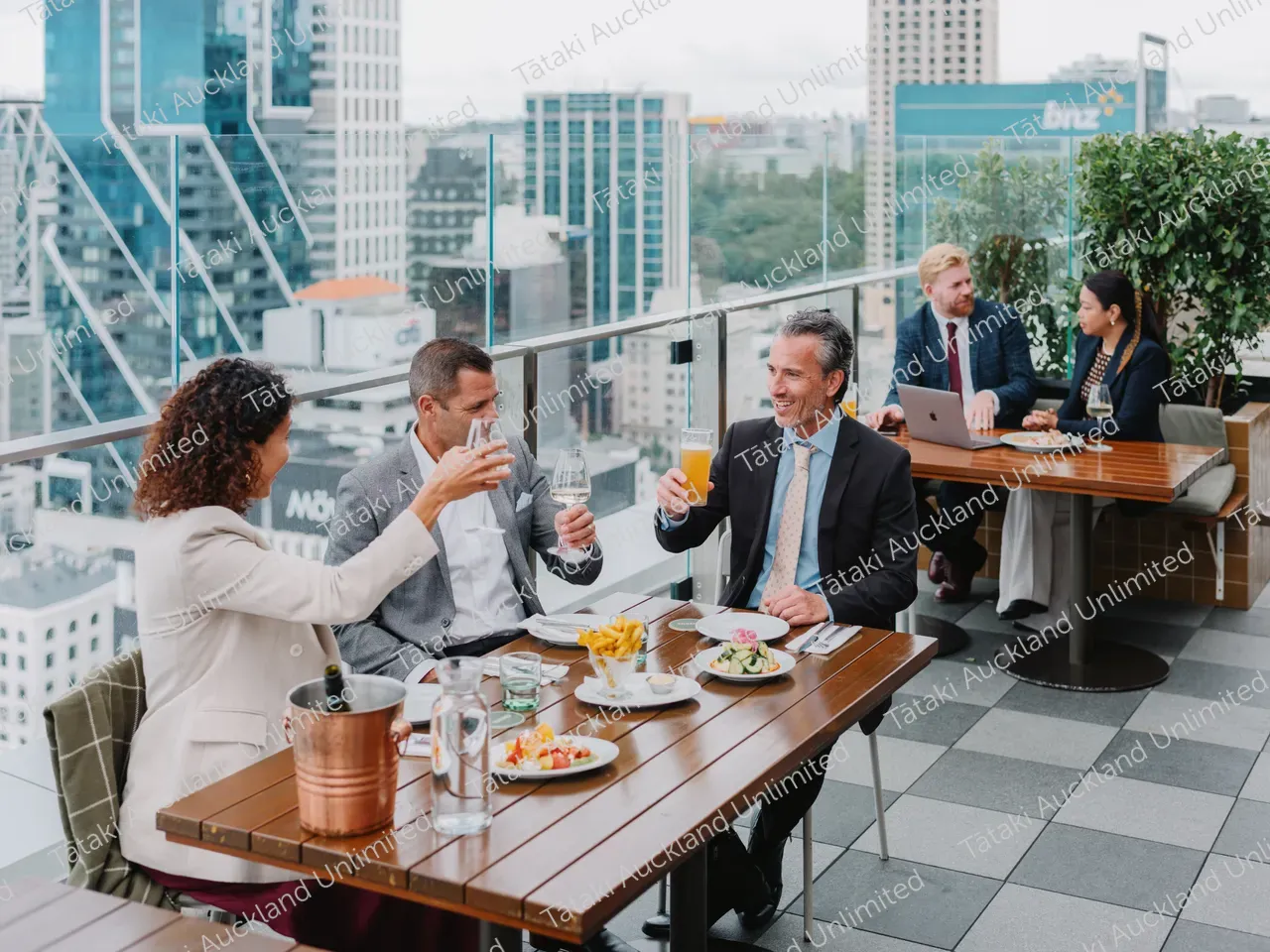 Business professionals dine on a rooftop terrace with city skyline views 4