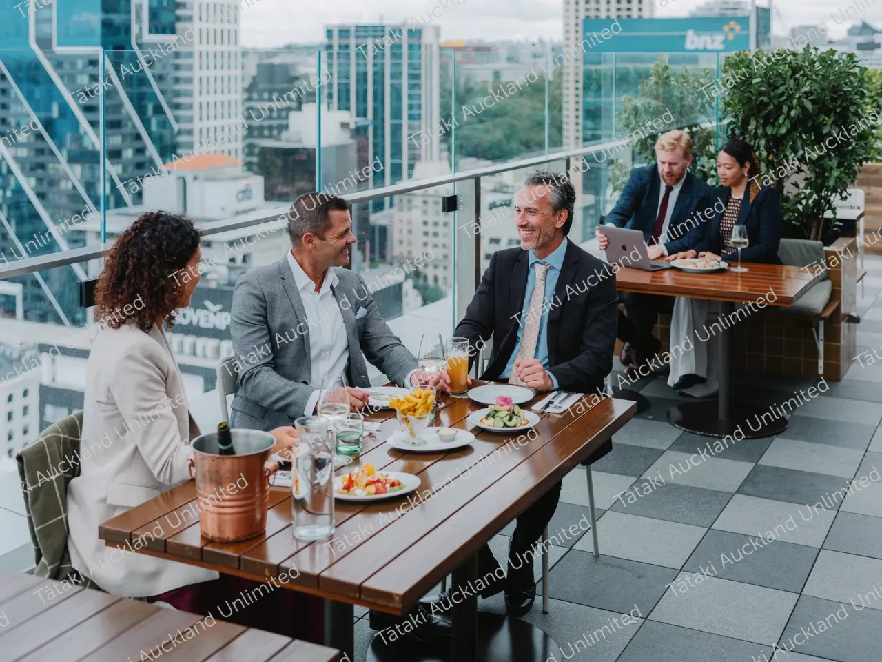 Business professionals dine on a rooftop terrace with city skyline views 5