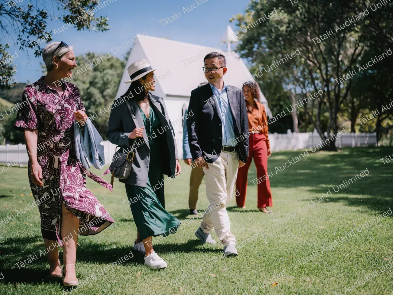 Group of business professionals walk the lawns of Waiheke vineyard 