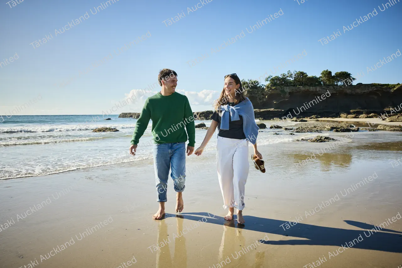 Couple walk on Tāwharanui Beach 4