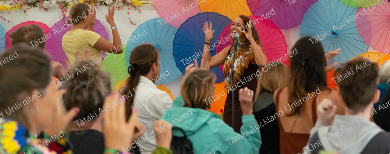 lady singing to crowd with colourful background