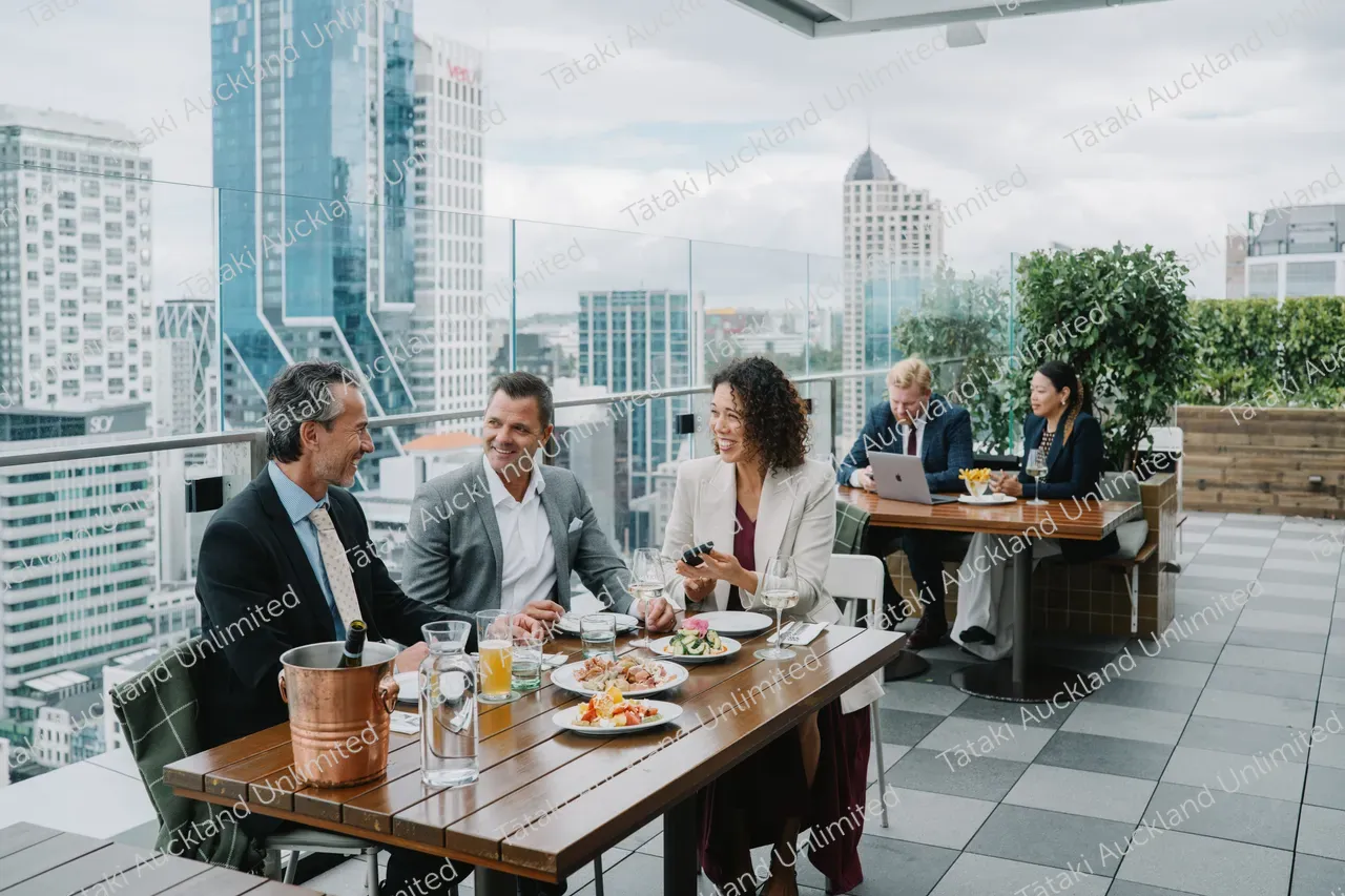 Business professionals dine on a rooftop terrace with city skyline views 10
