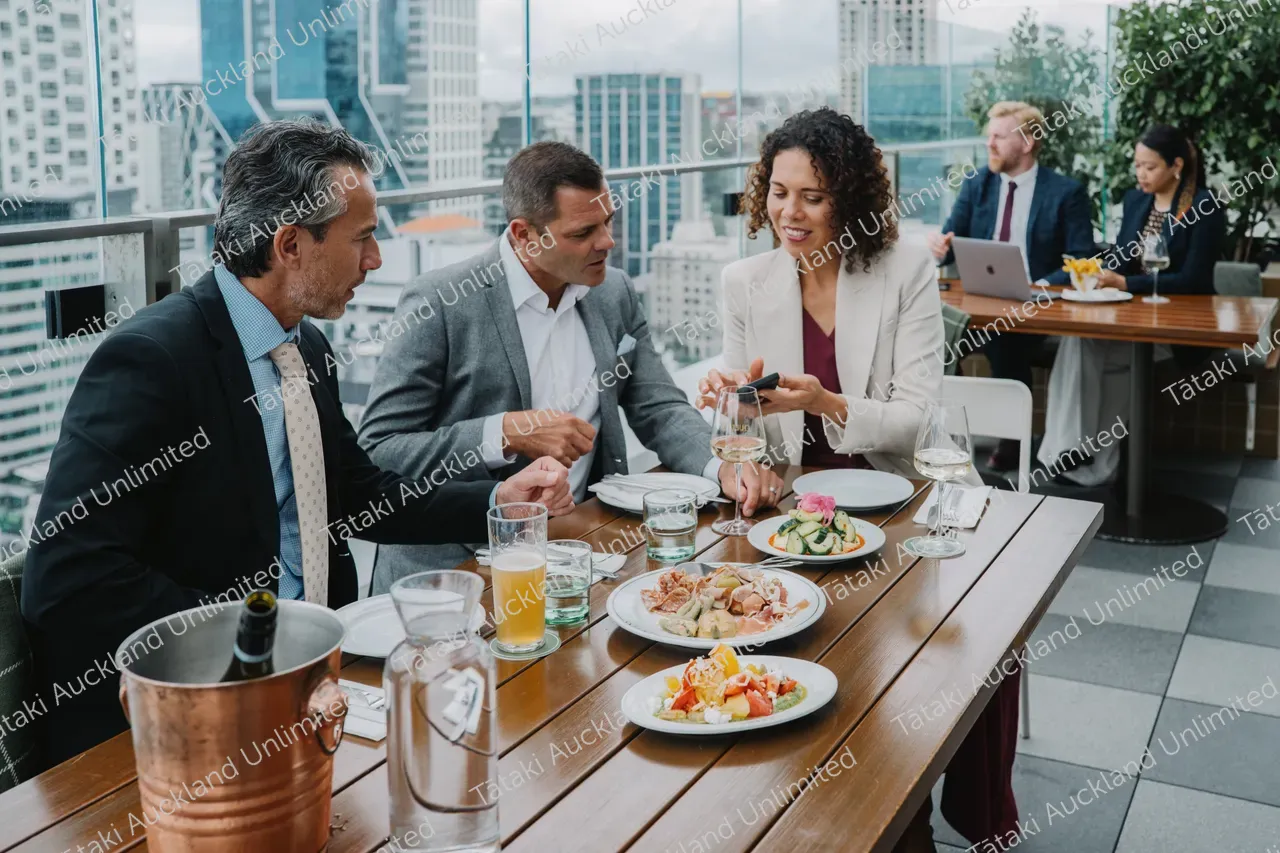 Business professionals dine on a rooftop terrace with city skyline views 9