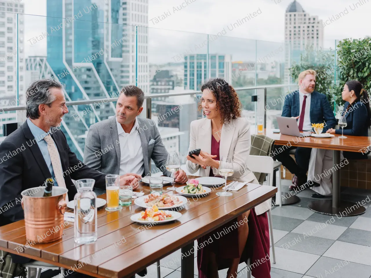 Business professionals dine on a rooftop terrace with city skyline views 7