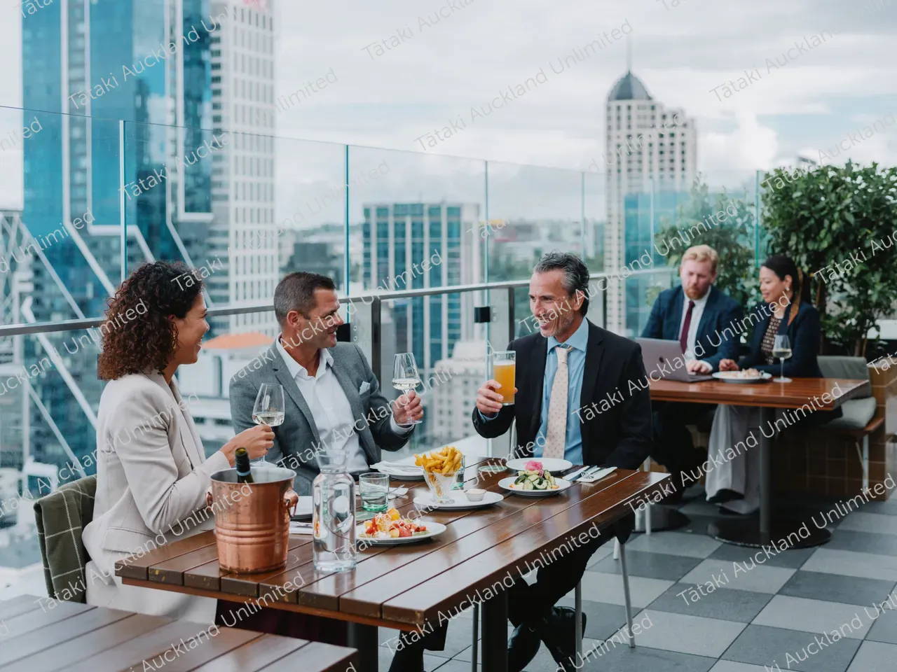 Business professionals dine on a rooftop terrace with city skyline views 3