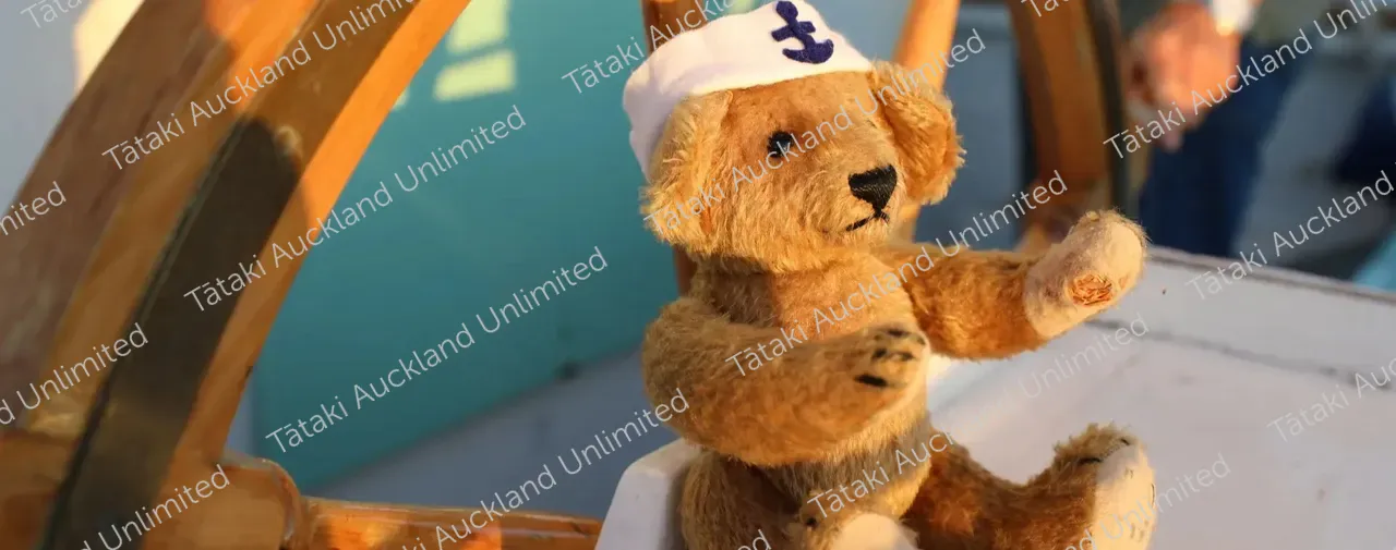Teddy bear on boat by wheel with sailors hat and anchor