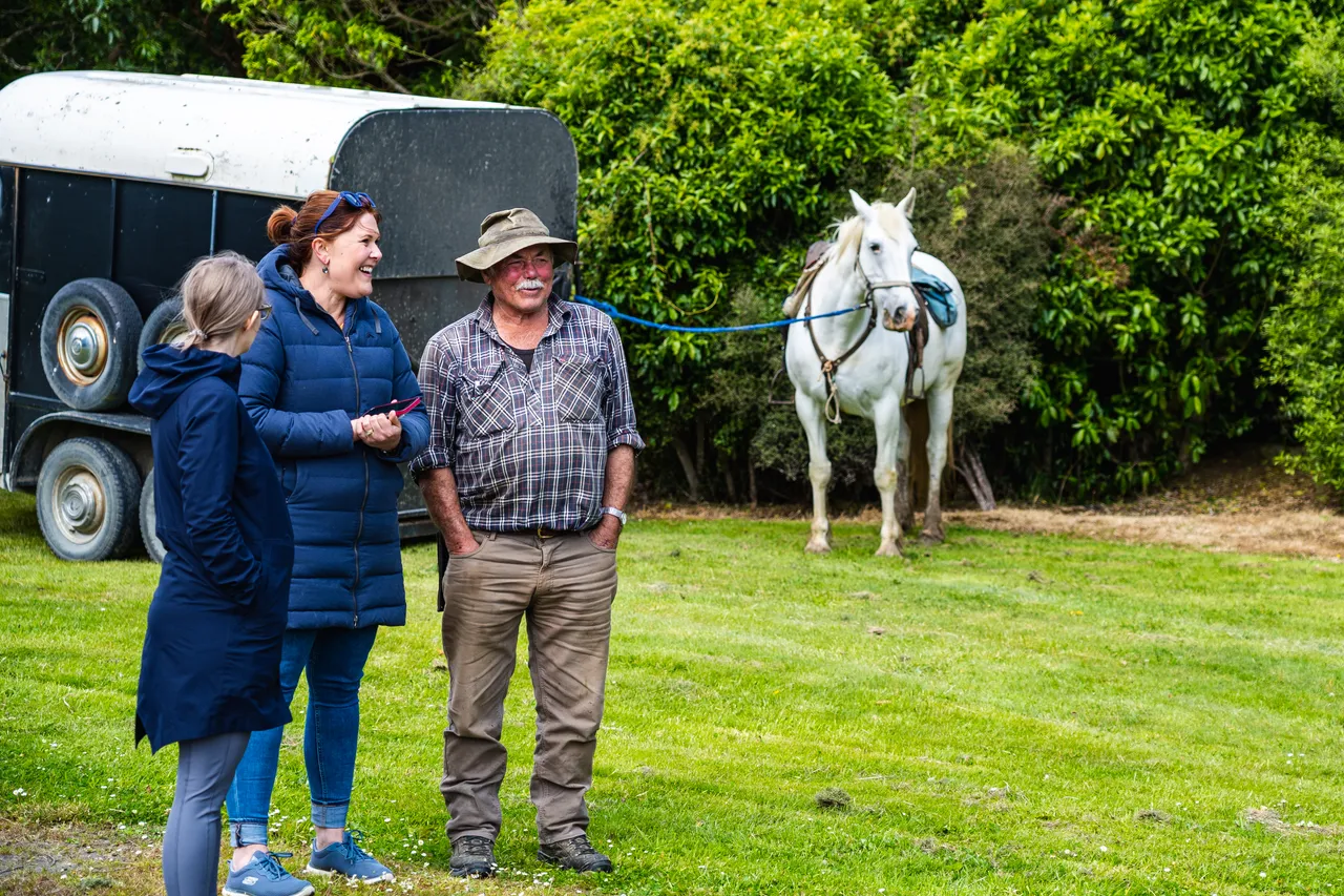 People with horse standing on grass