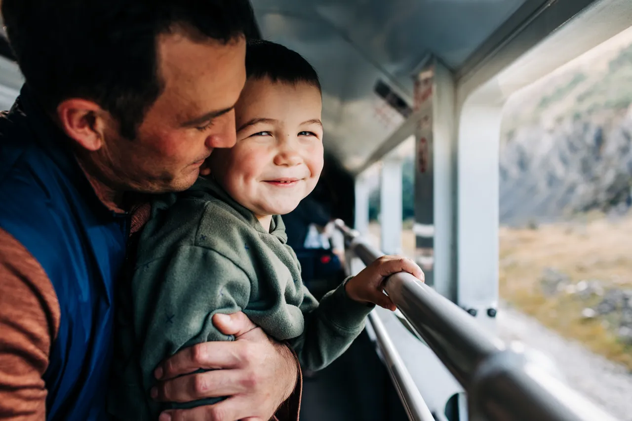 Father and son enjoying looking out of the open air carriage