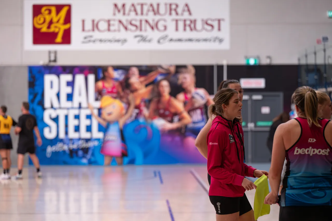 Netball players stand at side of Netball court